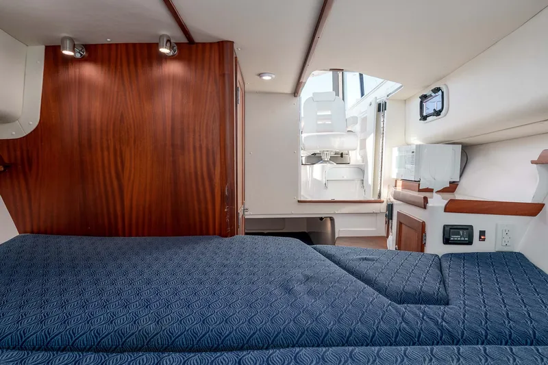 Caroline II Yacht Photos Pics 2021 NorthCoast 285 HT cabin interior with blue bedding and wooden accents.