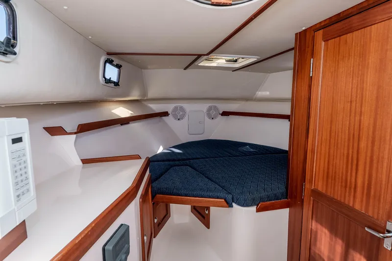 Caroline II Yacht Photos Pics 2021 NorthCoast 285 HT cabin interior with wood accents and blue bedding.