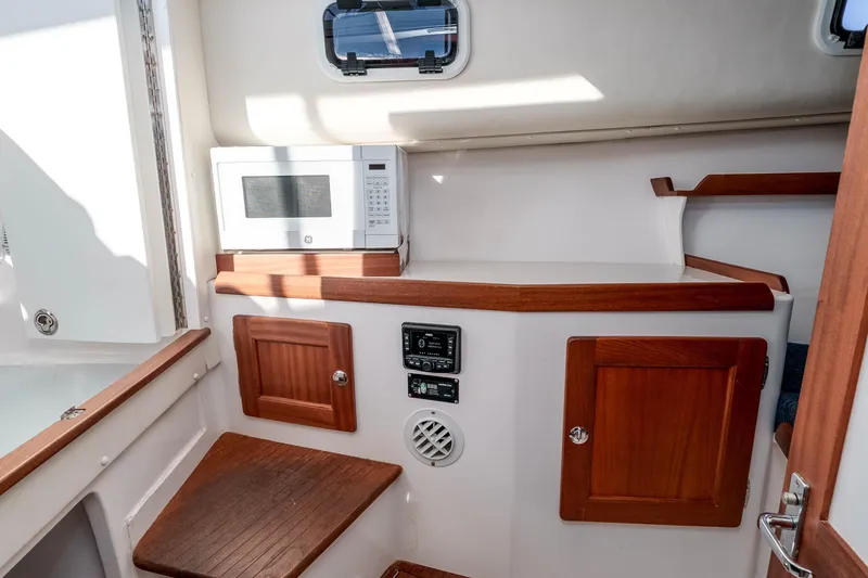 Caroline II Yacht Photos Pics 2021 NorthCoast 285 HT cabin interior with microwave and wooden cabinetry.
