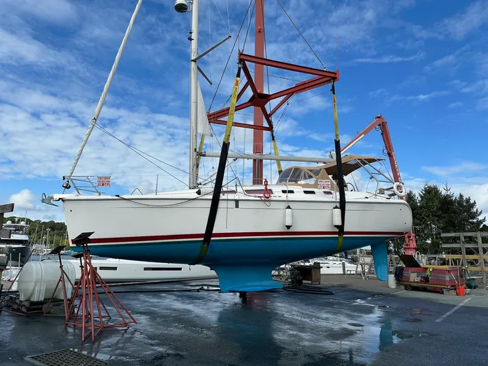  Yacht Photos Pics Hunter 38 sailboat from 2005 in dry dock, suspended for maintenance under a clear sky.