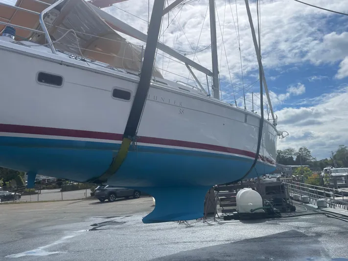  Yacht Photos Pics 2005 Hunter 38 sailboat suspended for maintenance under a partly cloudy sky.
