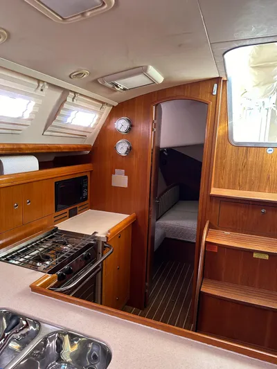  Yacht Photos Pics Interior of 2005 Hunter 38 sailboat with wood finish and compact kitchen area.