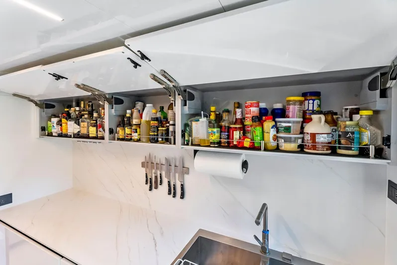  Yacht Photos Pics Modern yacht kitchen with open cabinets, condiments, knives, and sleek design on 2020 Ferretti Yachts 920.