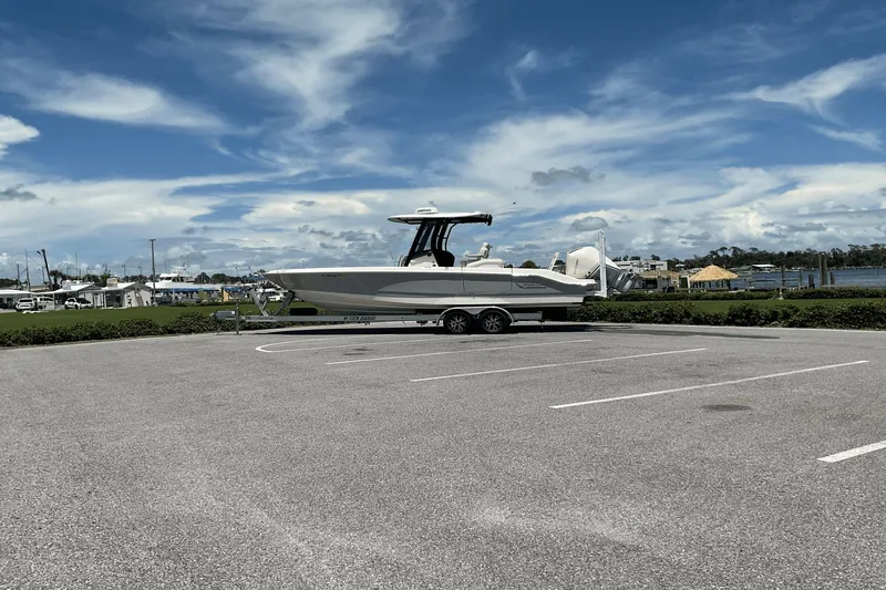  Yacht Photos Pics 2024 Boston Whaler 28 Dauntless boat on trailer in parking lot, under blue sky.