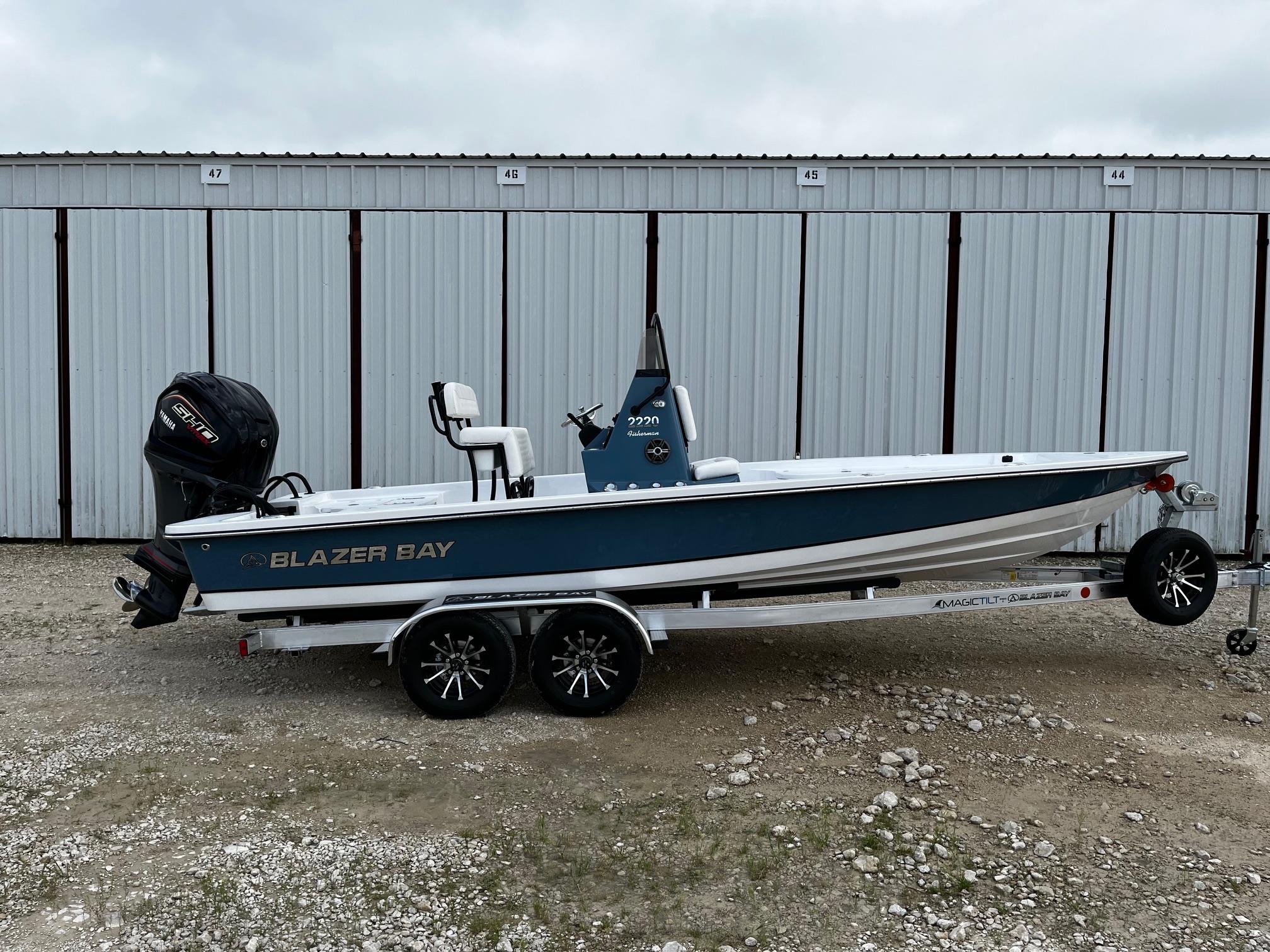 2025 Blazer Bay 2220 Fisherman boat on trailer, parked in front of storage units.