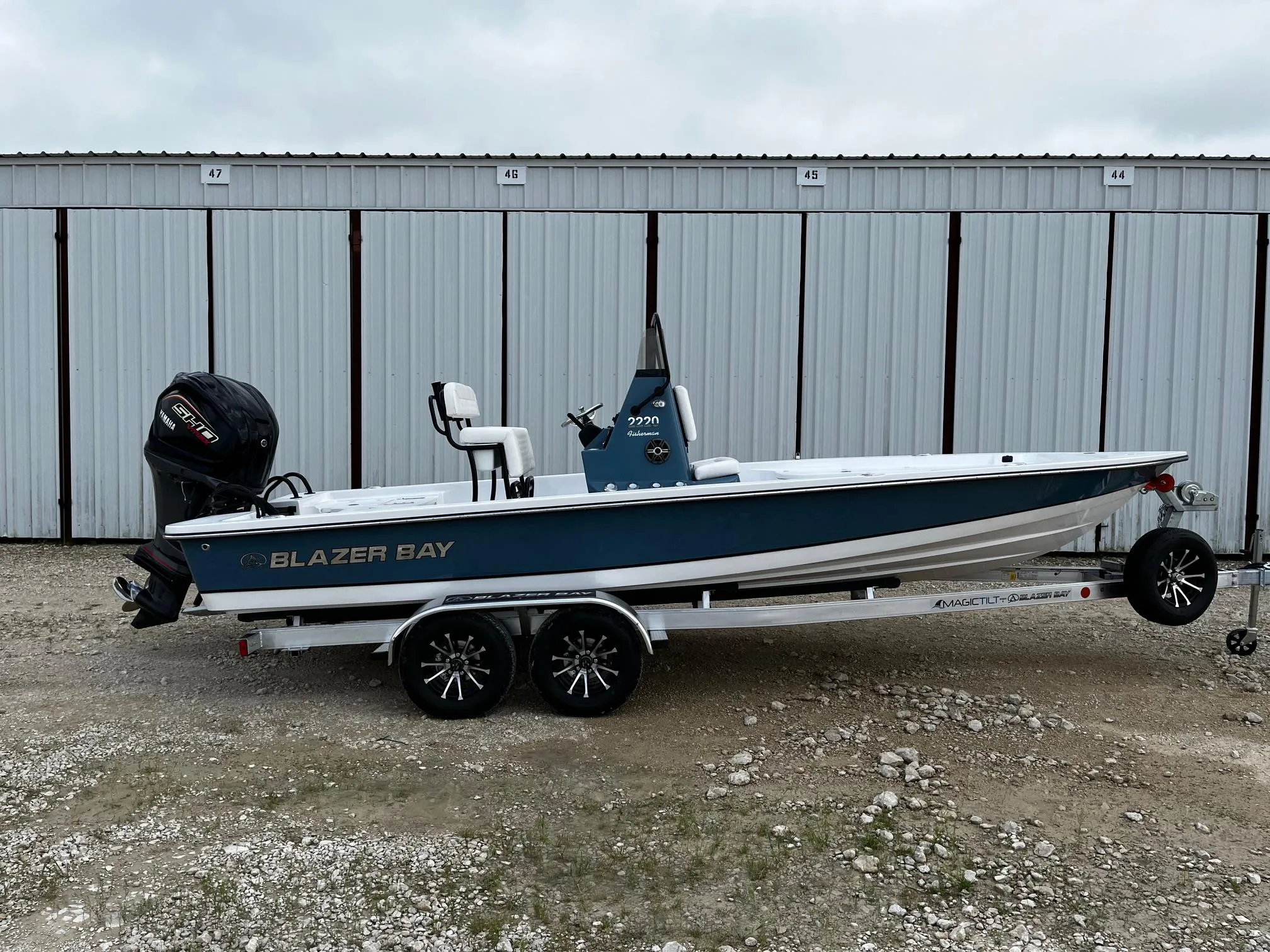 2025 Blazer Bay 2220 Fisherman boat on trailer, parked in front of storage units.