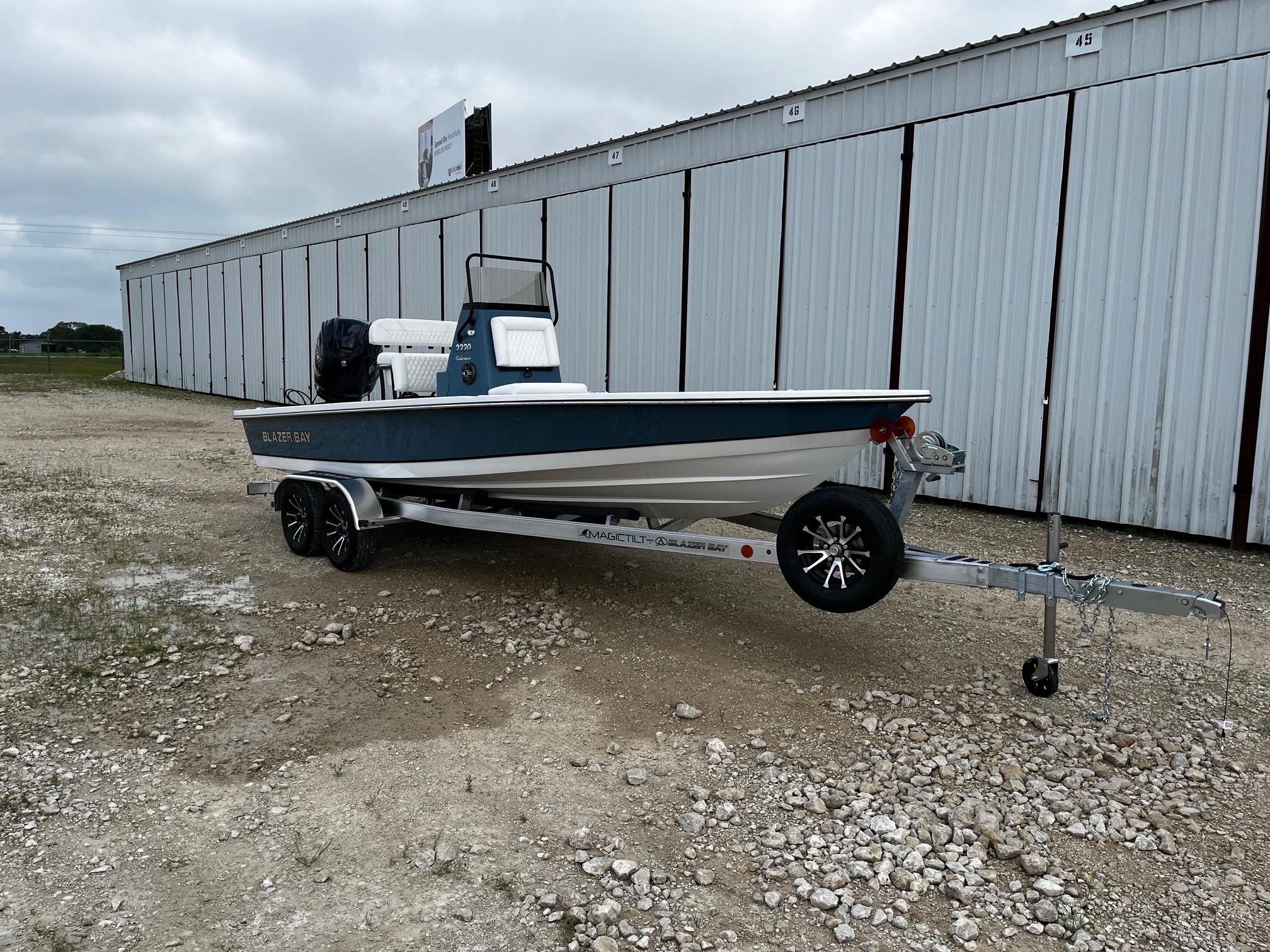 2025 Blazer Bay 2220 Fisherman boat on trailer, parked near storage units.