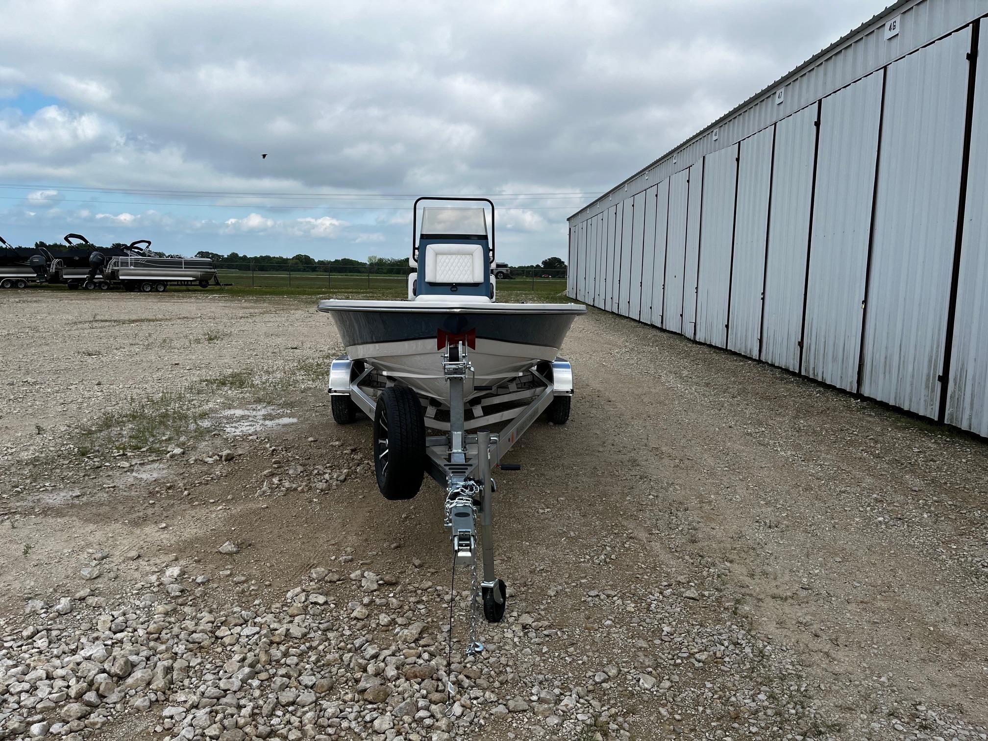 2025 Blazer Bay 2220 Fisherman boat on trailer, parked on gravel near a large building.