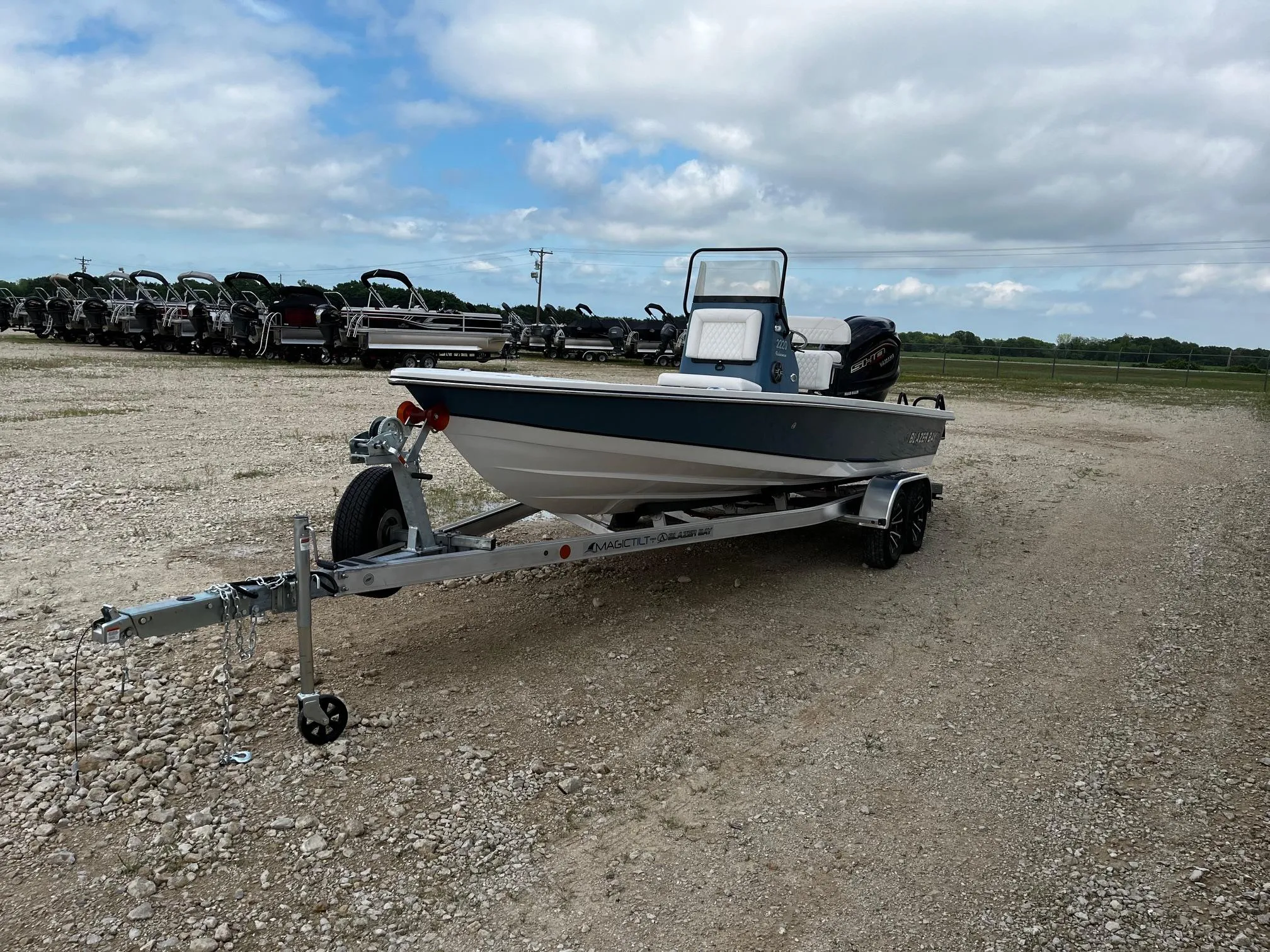 2025 Blazer Bay 2220 Fisherman boat on trailer in gravel lot under cloudy sky.