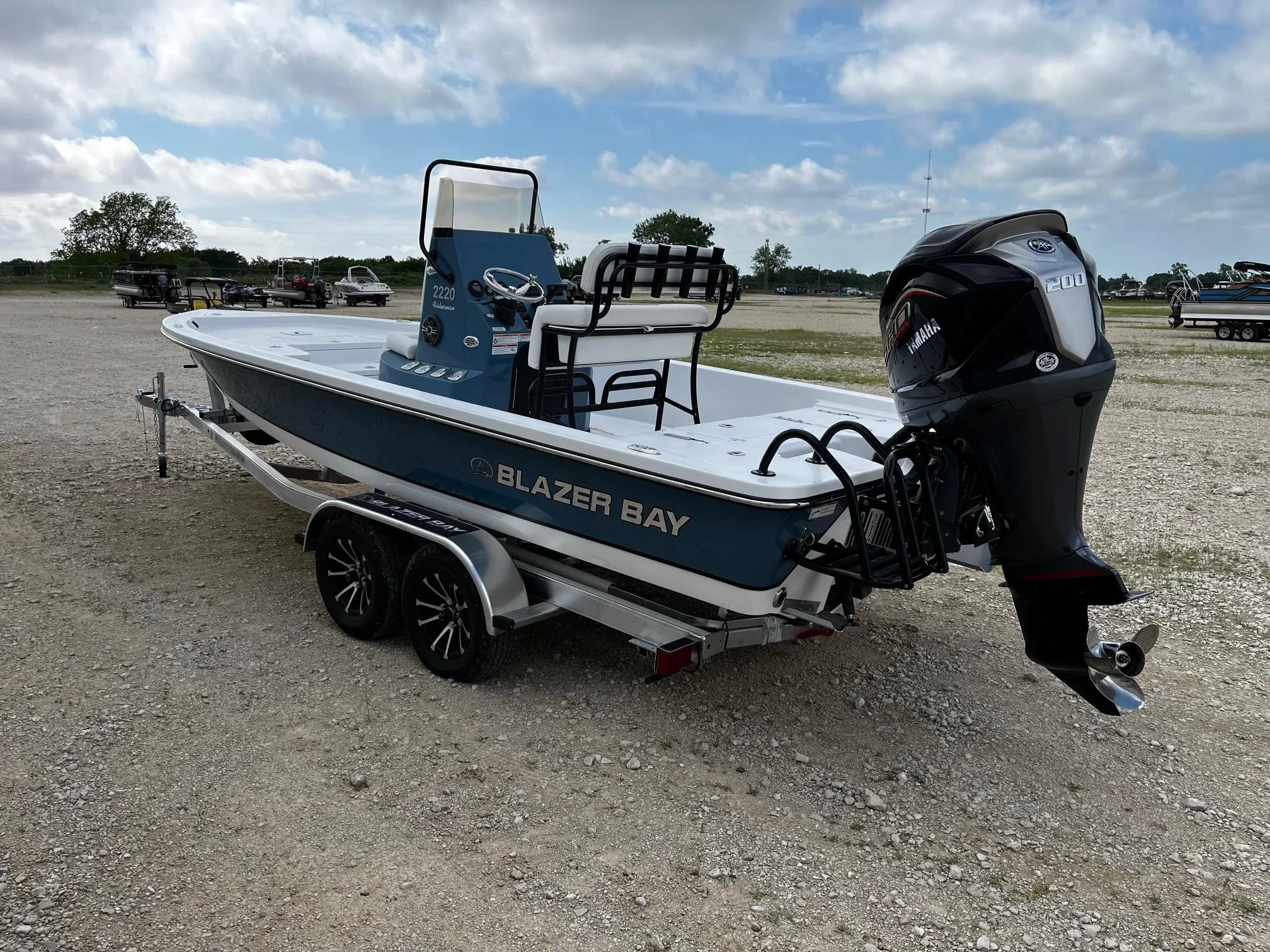 2025 Blazer Bay 2220 Fisherman boat on trailer, parked outdoors under cloudy sky.