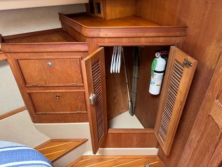 Odyssey Yacht Photos Pics Wooden interior storage with open cabinet, hangers, and fire extinguisher on Island Packet 380 yacht.