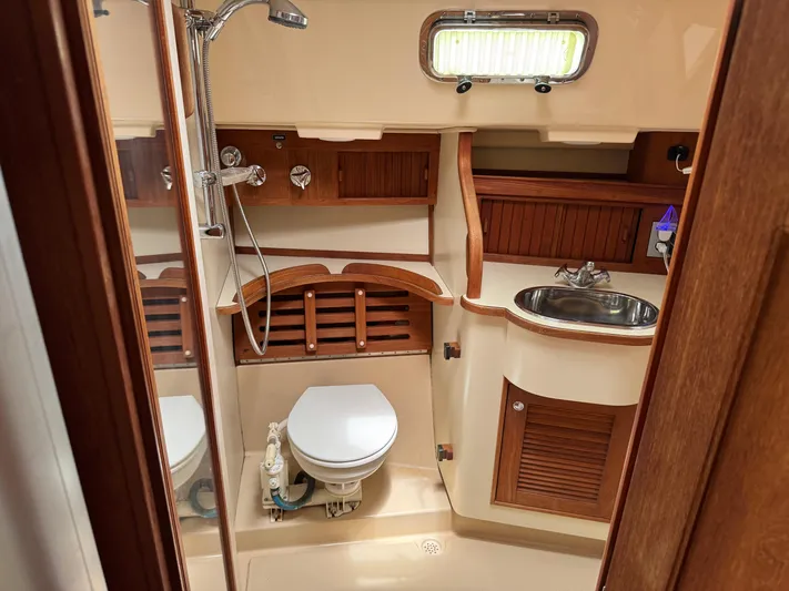 Odyssey Yacht Photos Pics Island Packet 380 yacht bathroom, 2002 model, featuring wooden cabinetry, toilet, sink, and shower.