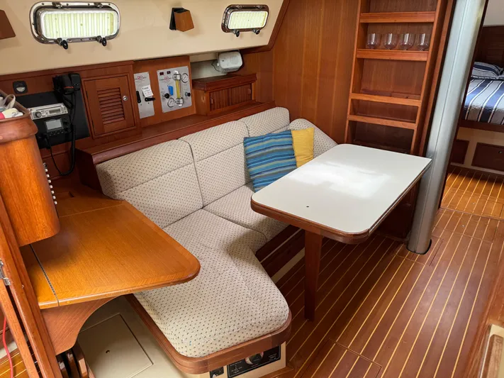 Odyssey Yacht Photos Pics Cozy interior of 2002 Island Packet 380 sailboat with cushioned seating and wooden table.