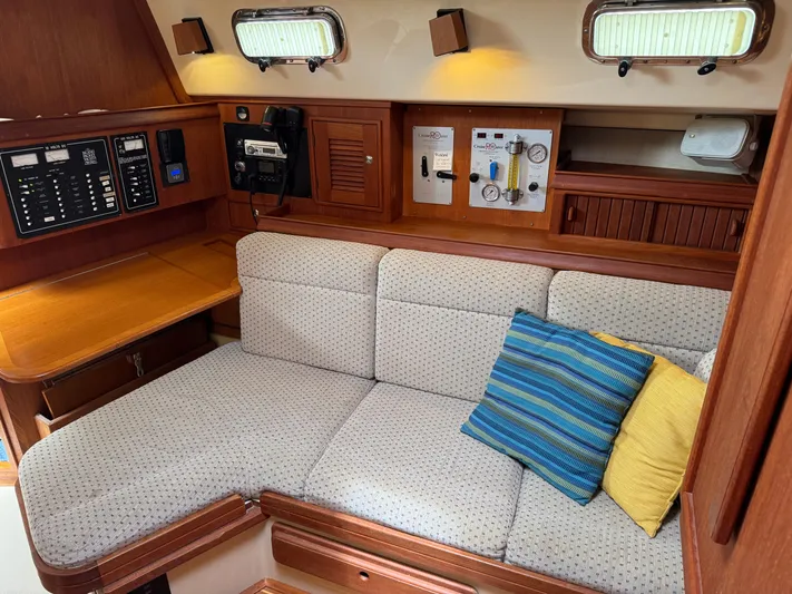 Odyssey Yacht Photos Pics Cozy interior of 2002 Island Packet 380 sailboat with cushioned seating and control panels.
