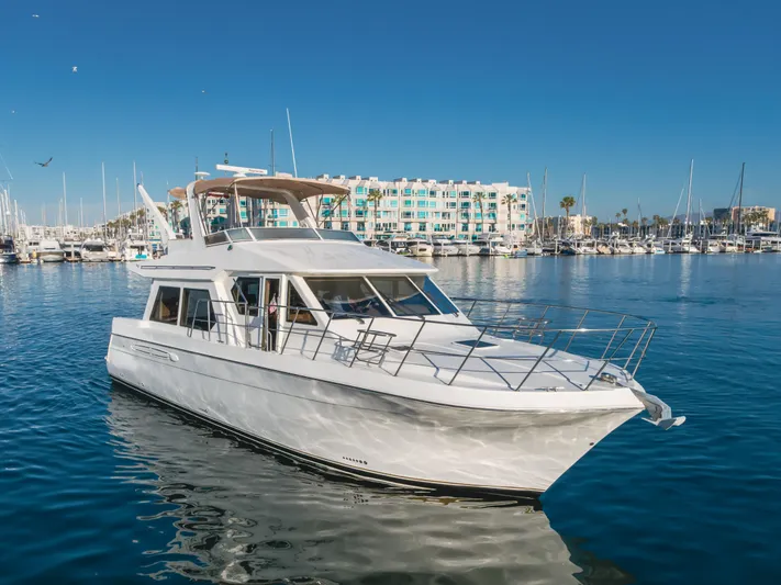 Love Life Yacht Photos Pics 2007 Navigator Pilothouse yacht in marina, clear blue sky, waterfront buildings in background.