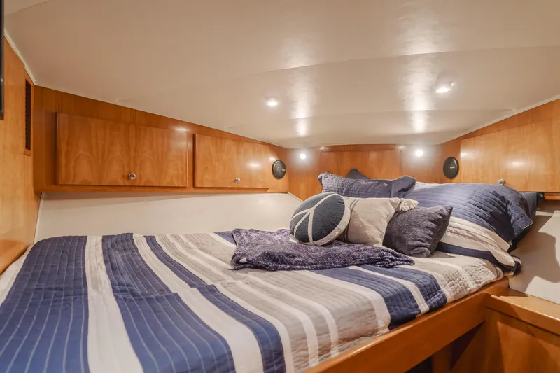 Love Life Yacht Photos Pics Luxurious 2007 Navigator Pilothouse bedroom with striped bedding and wooden cabinetry.