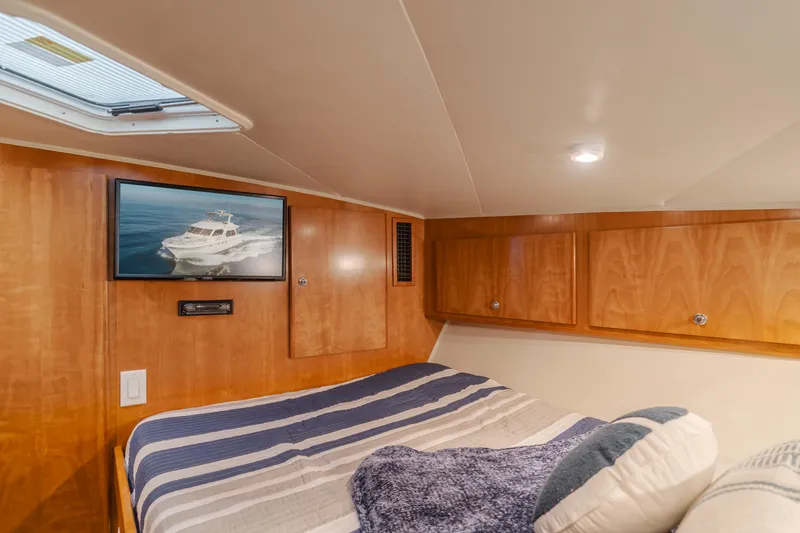 Love Life Yacht Photos Pics Cozy cabin interior of 2007 Navigator Pilothouse yacht with bed, TV, and wooden cabinets.