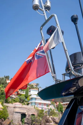  Yacht Photos Pics 2015 Riva 63 Virtus yacht with flags, against a coastal backdrop.