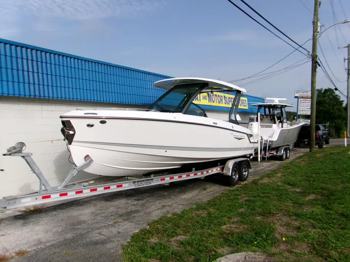  Yacht Photos Pics 2025 Monterey Elite 27 OB boat on trailer, parked outside a blue-roofed building.