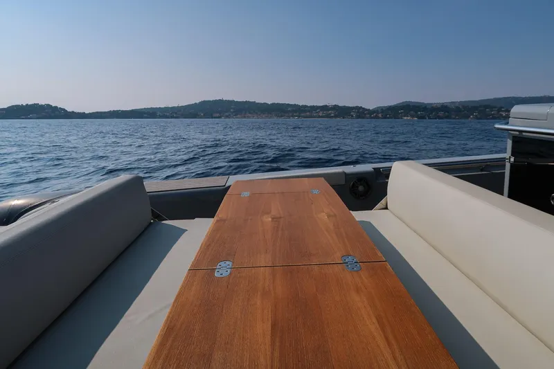  Yacht Photos Pics 2023 Pirelli 42 yacht with wooden table, scenic ocean view, and distant hills.