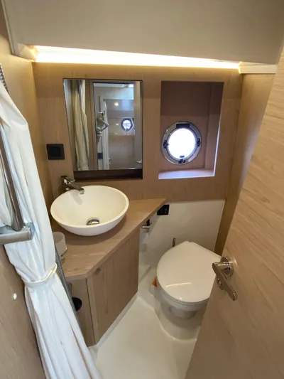  Yacht Photos Pics 2023 Beneteau Swift Trawler 41 Fly bathroom with modern sink, toilet, and porthole window.