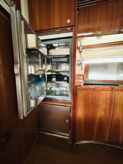  Yacht Photos Pics Open refrigerator inside 2006 Pershing 46 yacht, showcasing wooden interior and stocked shelves.