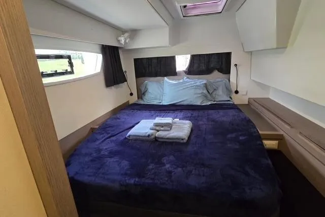 Island Nomad Yacht Photos Pics Luxurious bedroom interior of 2022 Fountaine Pajot Tanna 47 catamaran with cozy bedding.