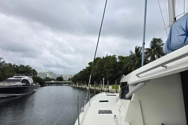 Island Nomad Yacht Photos Pics 2022 Fountaine Pajot Tanna 47 catamaran docked in a serene marina setting.