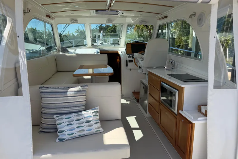 Pivot Yacht Photos Pics 2023 Back Cove 340 interior with seating, table, kitchenette, and helm station.