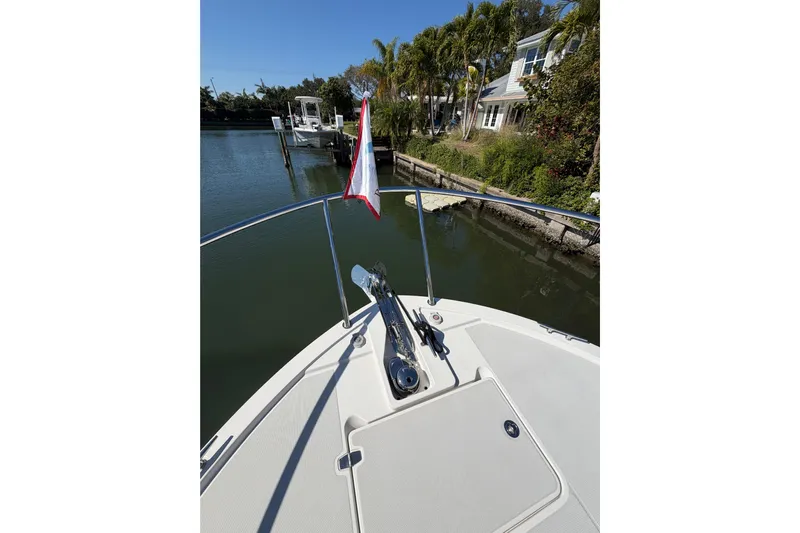 Pivot Yacht Photos Pics 2023 Back Cove 340 boat bow with anchor, docked near waterfront homes.