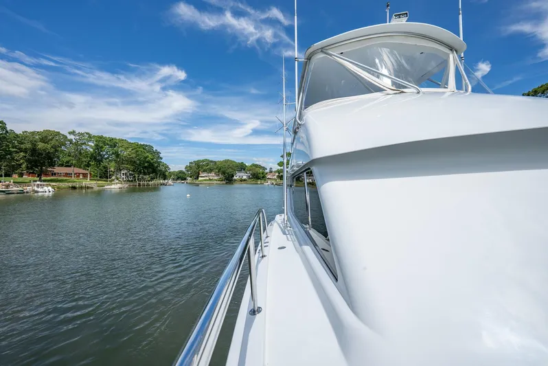 Fortitude Yacht Photos Pics 2001 Hatteras 50 Convertible yacht cruising on a serene river under a clear blue sky.