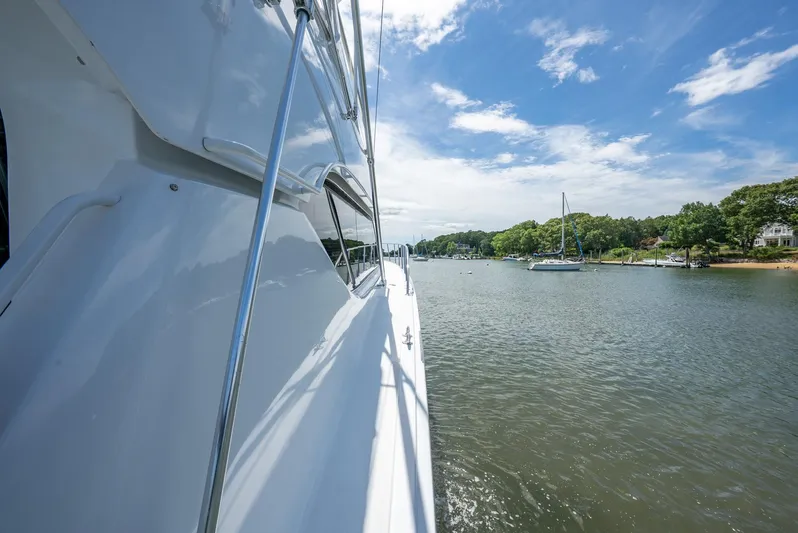 Fortitude Yacht Photos Pics Side view of a 2001 Hatteras 50 Convertible yacht on a serene waterway.