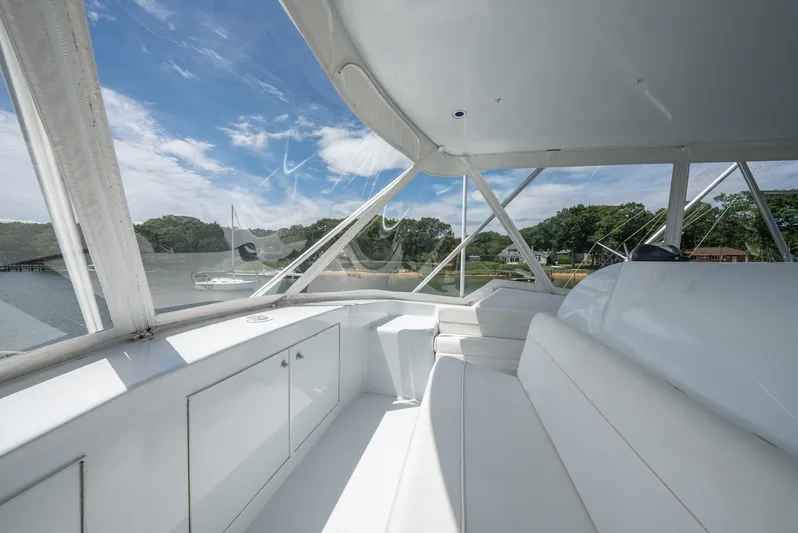 Fortitude Yacht Photos Pics Interior view of 2001 Hatteras 50 Convertible yacht with white seating and scenic water backdrop.