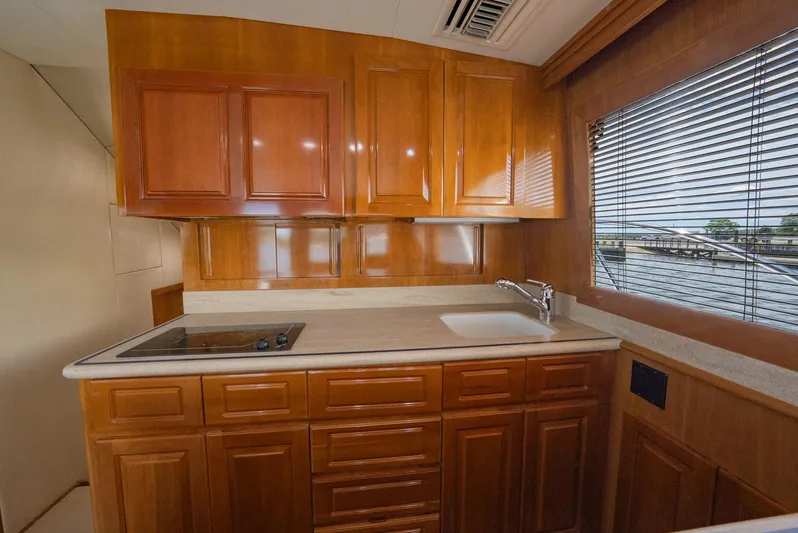 Fortitude Yacht Photos Pics Luxurious wooden kitchen interior of 2001 Hatteras 50 Convertible yacht with sink and stove.