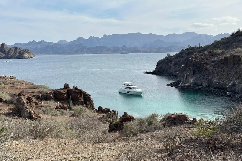 Matsu Yacht Photos Pics 2018 Ferretti Yachts 650 anchored in a serene, rocky coastal bay.