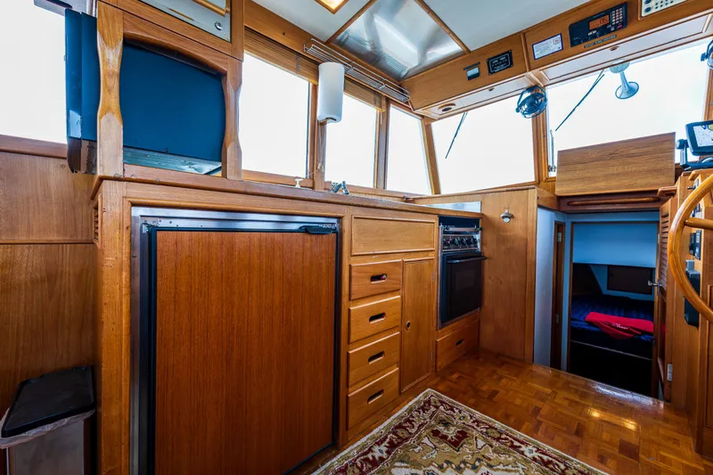 Skagit Song Yacht Photos Pics 1984 Grand Banks 36 Sedan interior with wooden cabinetry, kitchen appliances, and steering wheel.