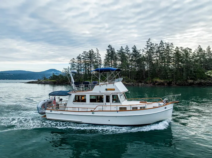 Skagit Song Yacht Photos Pics 1984 Grand Banks 36 Sedan cruising on scenic water with forested shoreline in the background.
