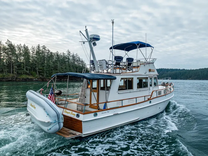 Skagit Song Yacht Photos Pics 1984 Grand Banks 36 Sedan cruising on a scenic waterway with forested shoreline.