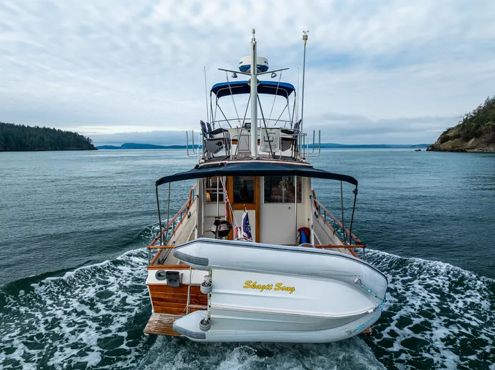 Skagit Song Yacht Photos Pics 1984 Grand Banks 36 Sedan cruising on open water, rear view with dinghy attached.
