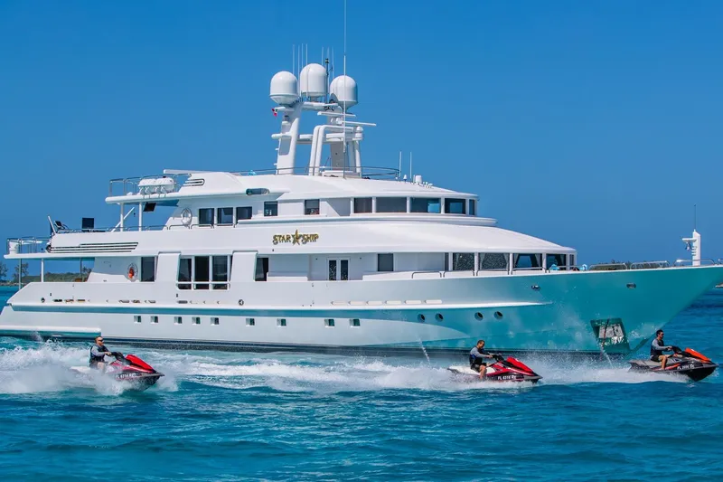 Starship Yacht Photos Pics Luxurious 1986 Van Mill 144 Motor Yacht with jet skis in vibrant blue waters.