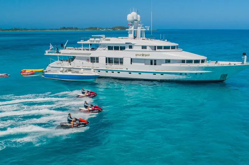 Starship Yacht Photos Pics Luxurious 1986 Van Mill 144 Motor Yacht with jet skis in turquoise waters.