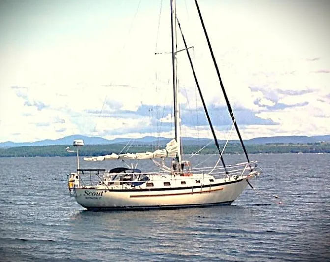 Scout Yacht Photos Pics Sailboat on calm water, Pacific Seacraft 34, 1998 model, with scenic mountain backdrop.