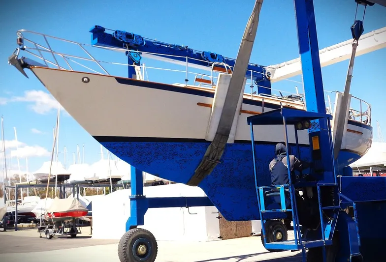 Scout Yacht Photos Pics 1998 Pacific Seacraft 34 sailboat being lifted by a blue crane at a marina.