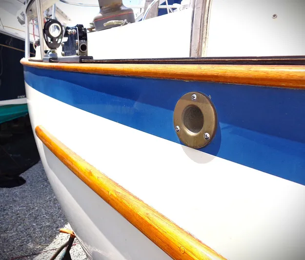 Scout Yacht Photos Pics Close-up of 1998 Pacific Seacraft 34 boat hull with blue stripe and wooden trim.