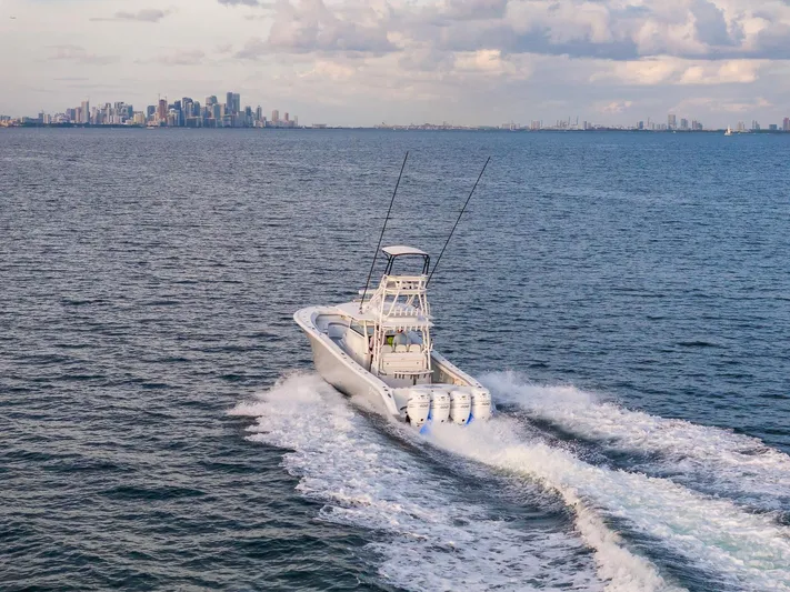  Yacht Photos Pics 2022 Yellowfin 42 boat cruising on open water with city skyline in background.