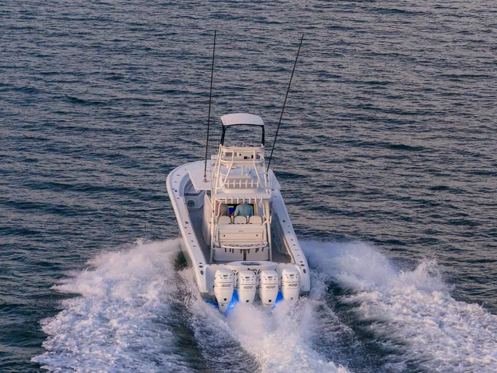  Yacht Photos Pics 2022 Yellowfin 42 boat cruising on open water with triple outboard engines.