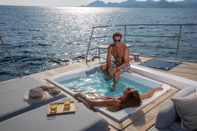 Serenissima III Yacht Photos Pics Couple relaxing in jacuzzi on 2025 Fountaine Pajot Thira 80 yacht, ocean view.