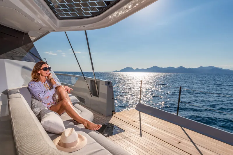 Serenissima III Yacht Photos Pics Woman relaxing on Fountaine Pajot Thira 80 yacht, 2025, with ocean view.