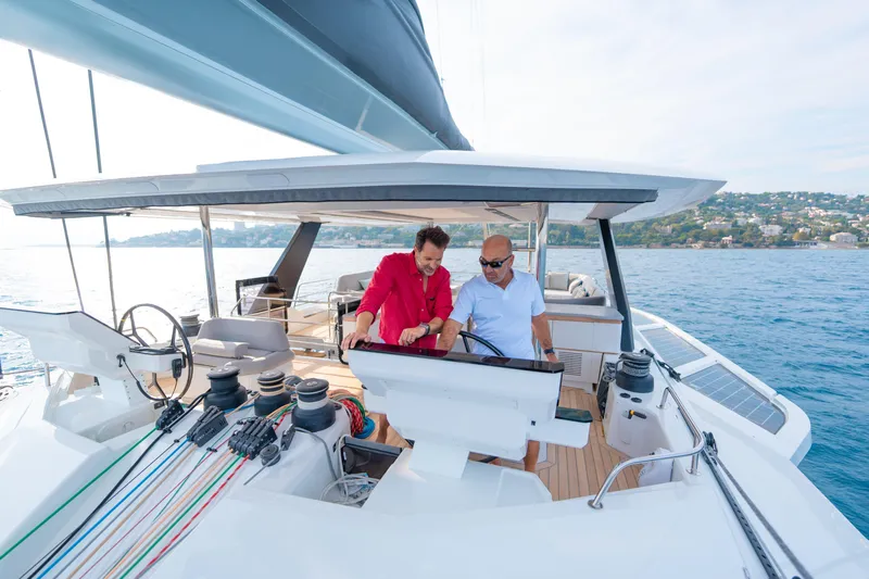 Serenissima III Yacht Photos Pics Two people navigating the 2025 Fountaine Pajot Thira 80 yacht on open water.