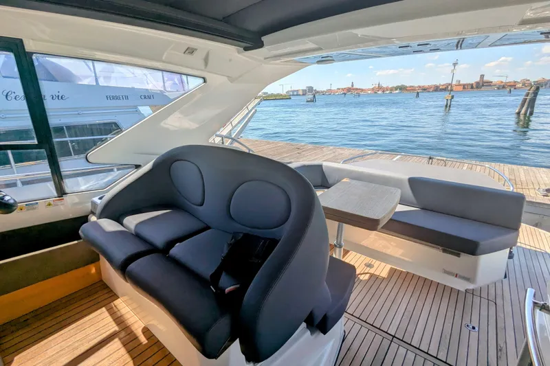 Yacht Photos Pics Interior view of 2016 Cranchi M 44 HT yacht with seating and table, docked by the water.
